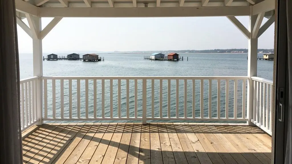 Vue sur le Bassin d'Arcachon depuis la terrasse d'une villa à Andernos, avec garde-corps blanc et eaux calmes